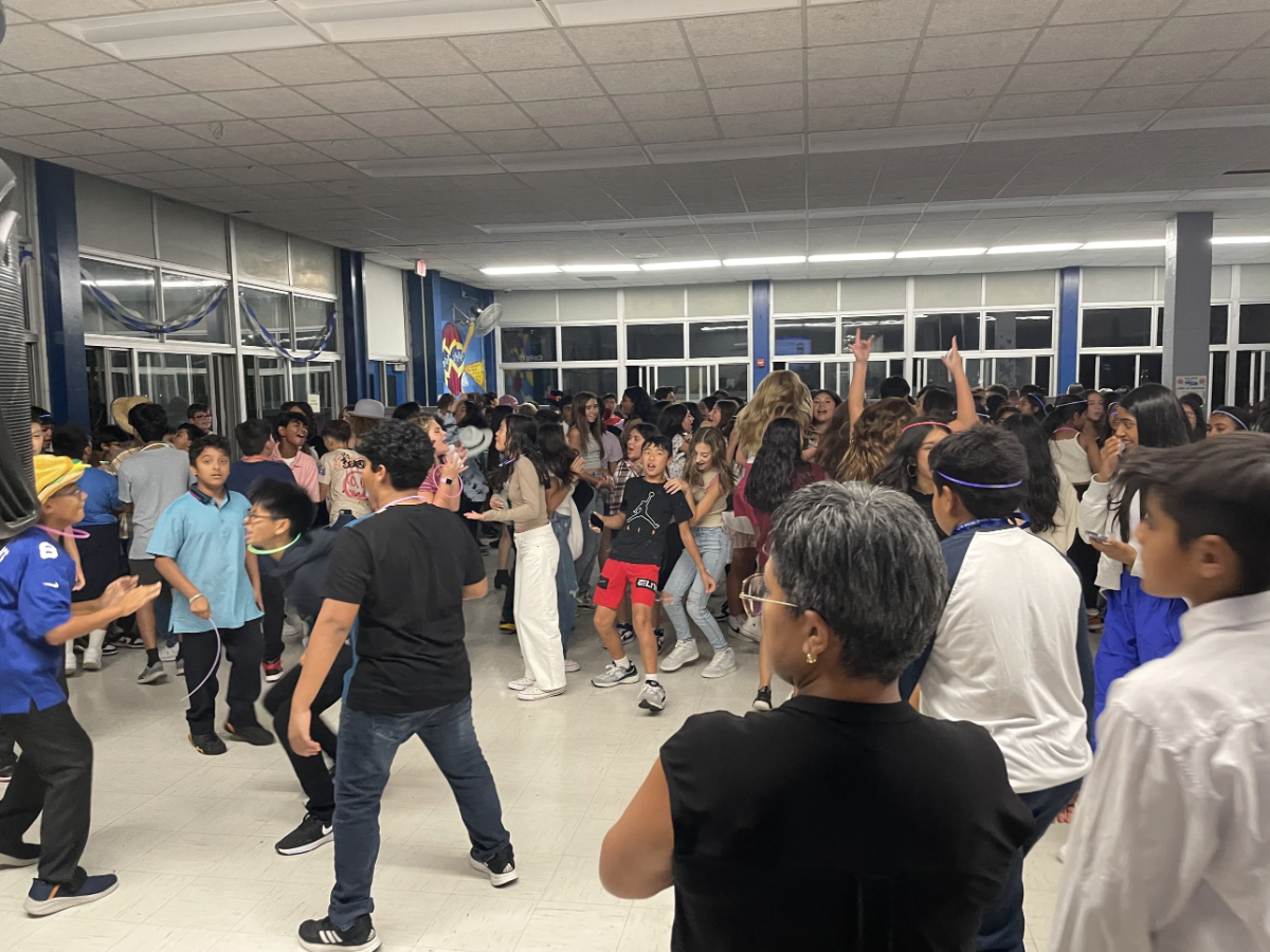 Seventh graders celebrate at the Blue and White dance, while class adviser Mrs. Pincay supervises.